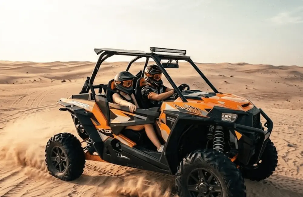 Conducteur et passagère dans un buggy biplace pendant une balade guidée dans les dunes d’Essaouira