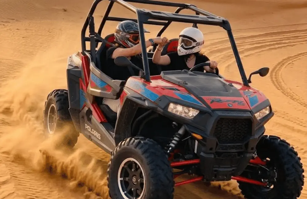 Conducteur et passagère casqués partageant une randonnée en buggy dans les dunes d’Essaouira