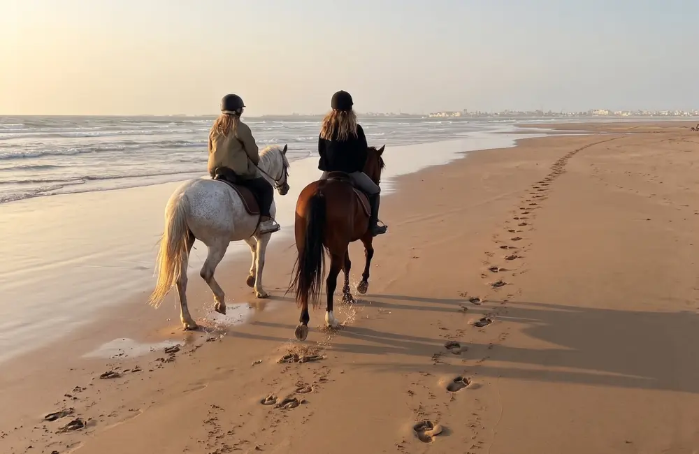 Deux cavaliers pendant une balade à cheval sur la plage d’Essaouira