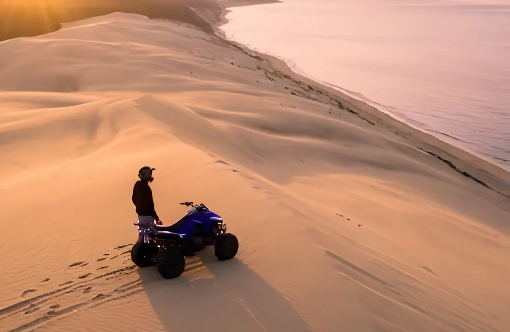 Pilote avec son quad sur une grande dune face à l’océan Atlantique