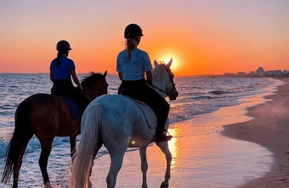 Cavaliers à cheval gravissant les crêtes de sable des dunes du Cap Sim à Essaouira