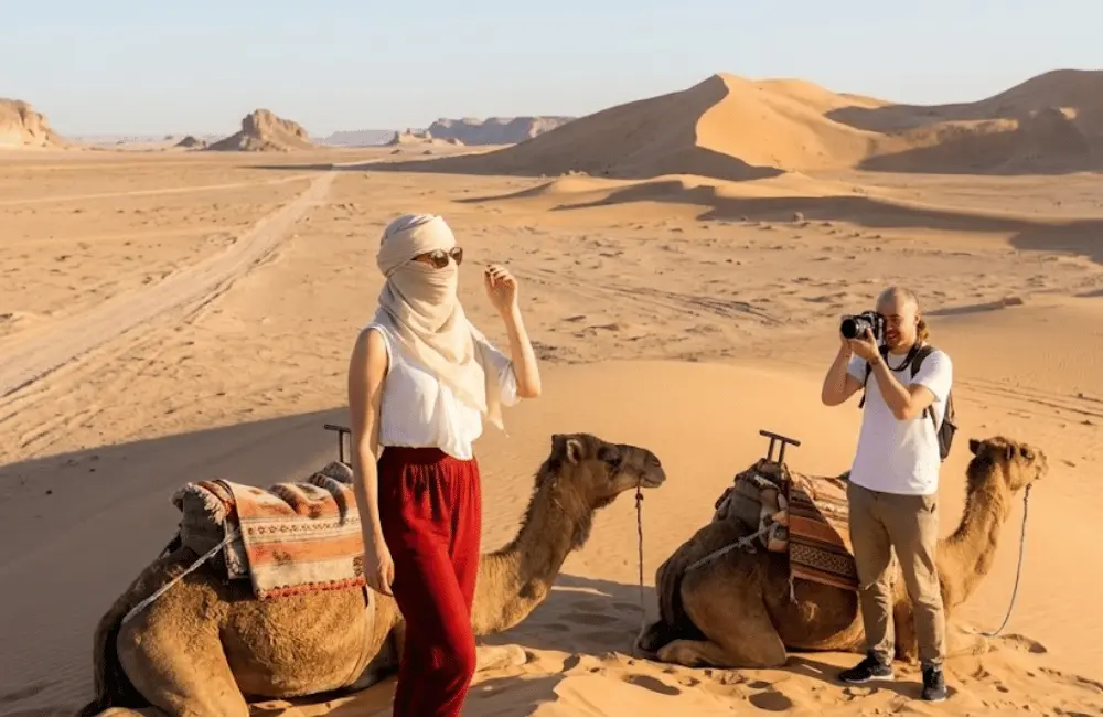 La pause photo dans les dunes Voyageur photographie sa partenaire pendant une pause de randonnée chamelière dans les dunes